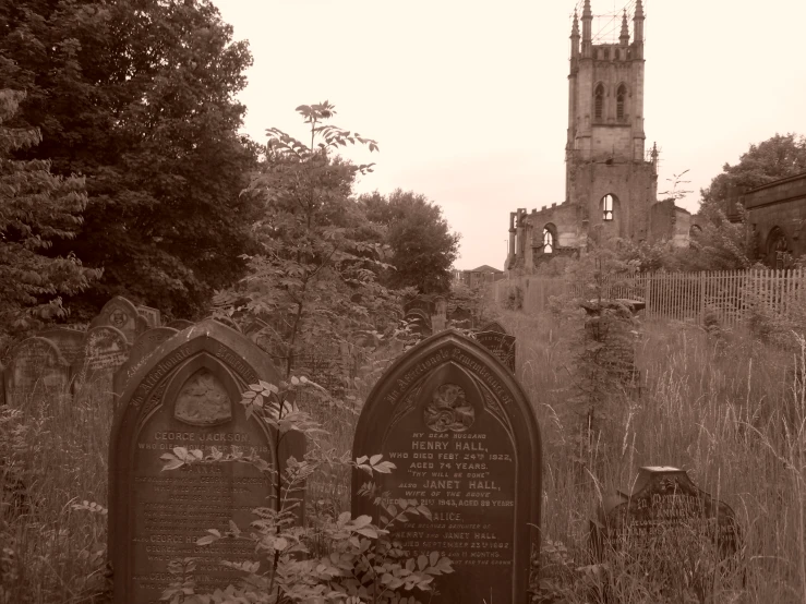 old tombstones sitting in the grass with a tower in the background