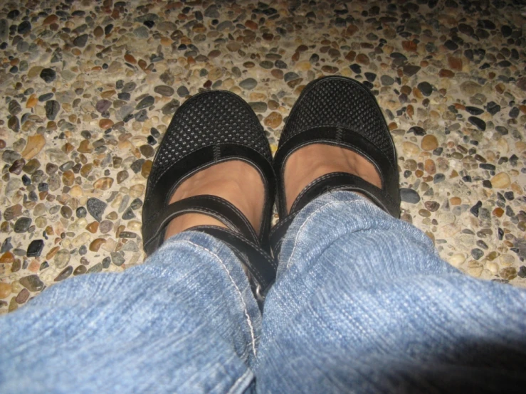 a person is wearing black heels with denim jeans