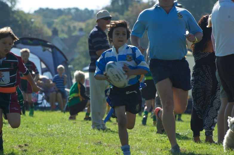 s run along the grass while a man holds a football