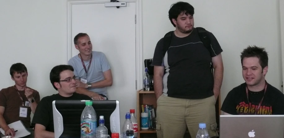 several men in a room with one on a computer and one sitting