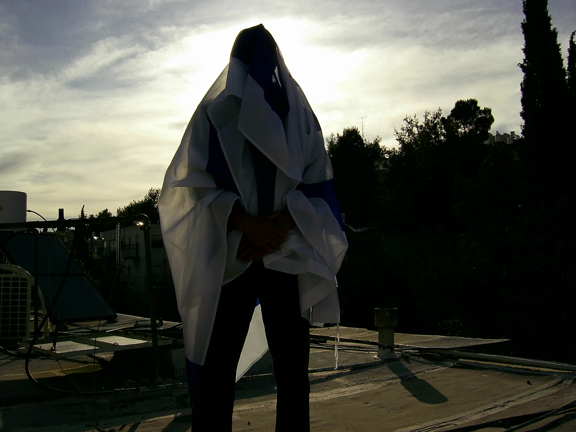 someone standing on the roof wearing a large white and blue coat