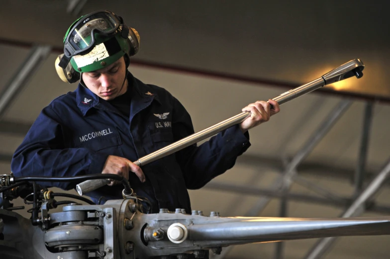 a man in uniform holds an adjustable tool to the frame of a plane