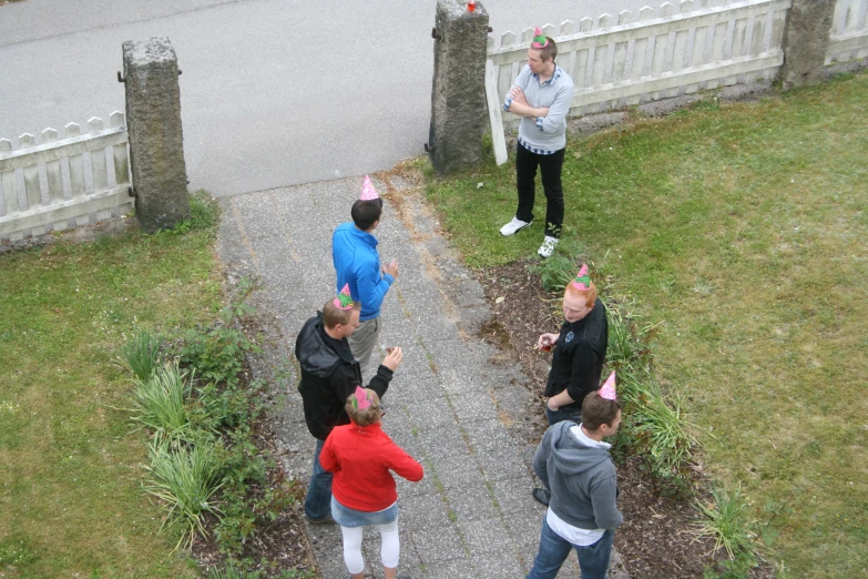 four people stand near a house and a white picket fence