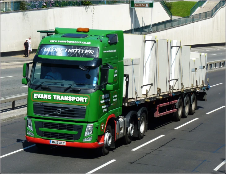 a green transport truck driving down the street