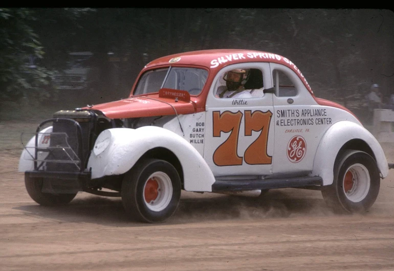 a white and red truck with a number 7 on it driving down a dirt road