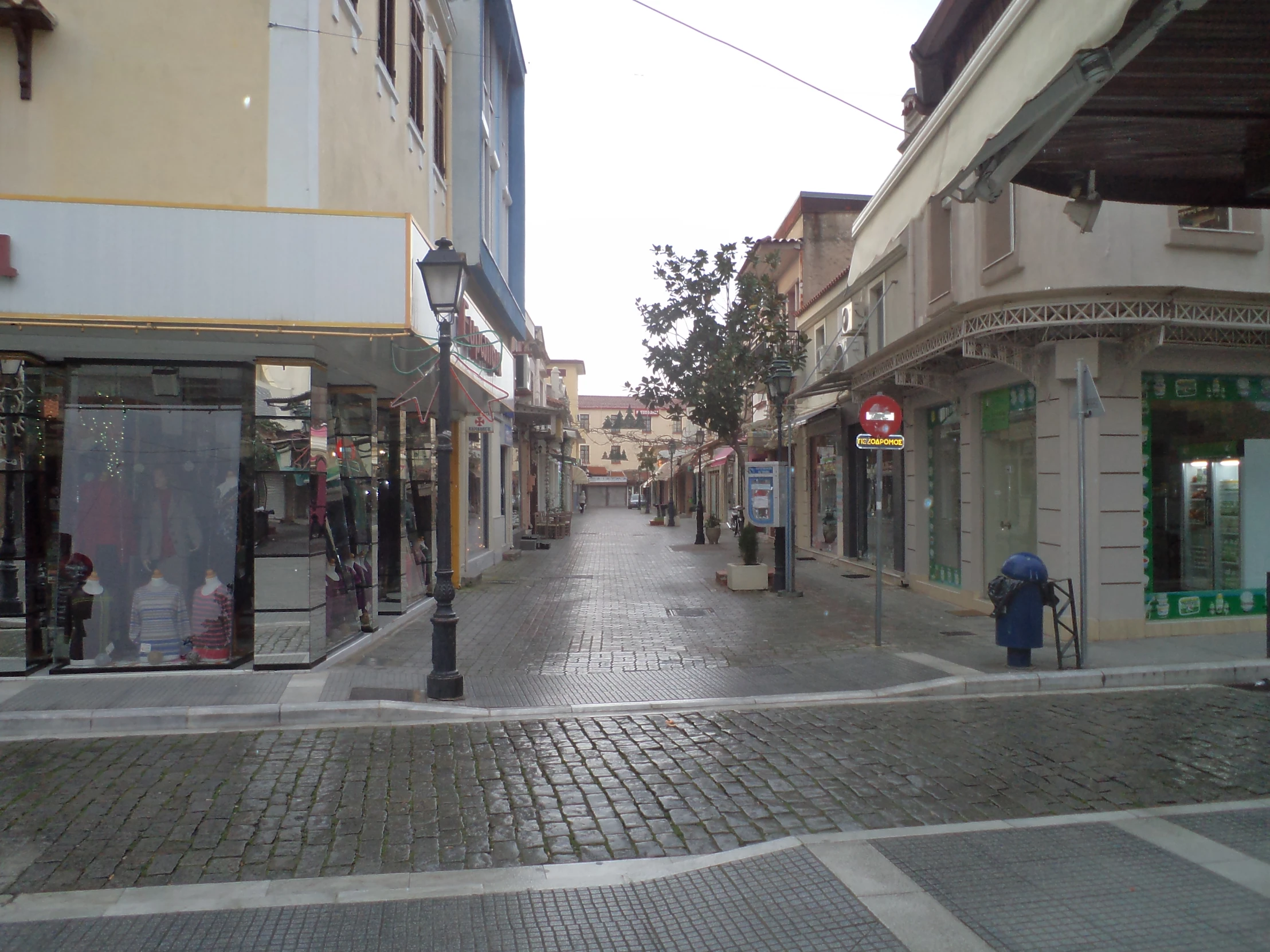 a wet street with shops on the sides and in the foreground