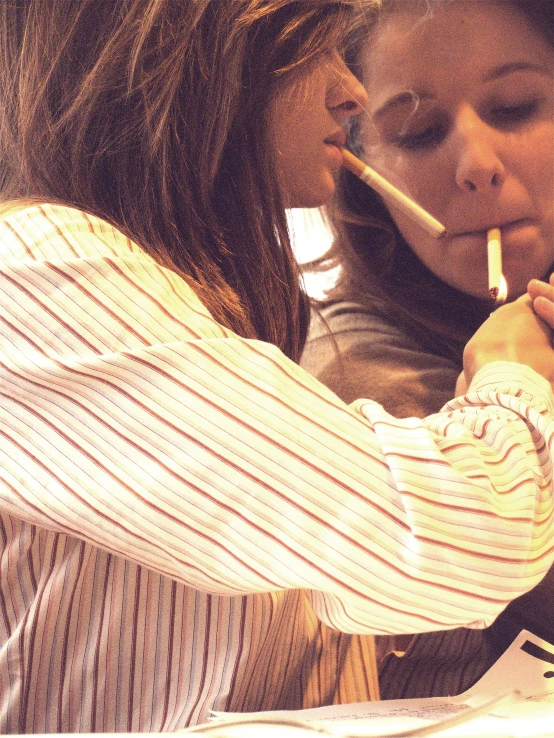 two girls are smoking as they watch soing