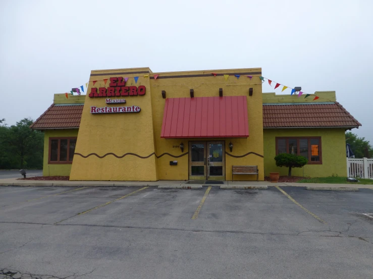 a restaurant is yellow and red outside in front of a parking lot