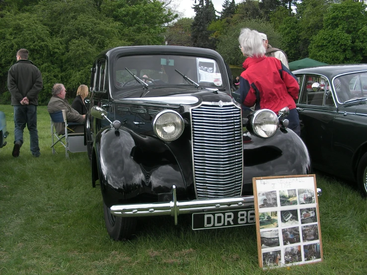 the people are standing around in front of some old cars