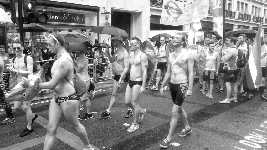 a group of men wearing underwear and sunglasses march in front of the crowd