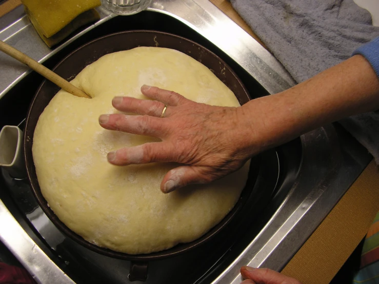 the person is kneading the dough into a pan