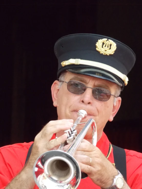 man wearing uniform playing the trombone in front of a microphone