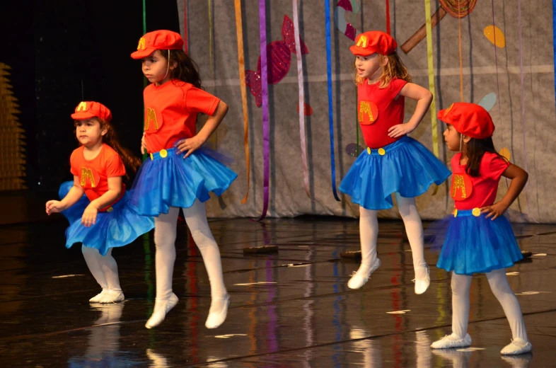 children in matching outfits are standing in the middle of a stage