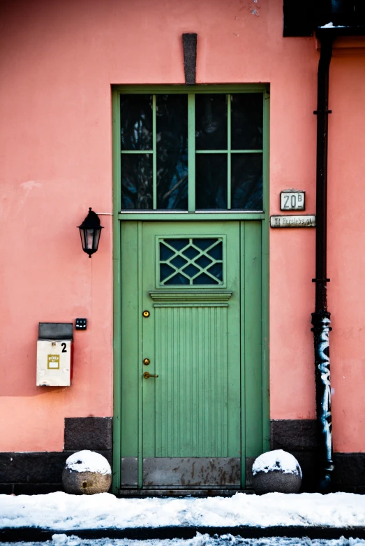 a green door and window on a pink building