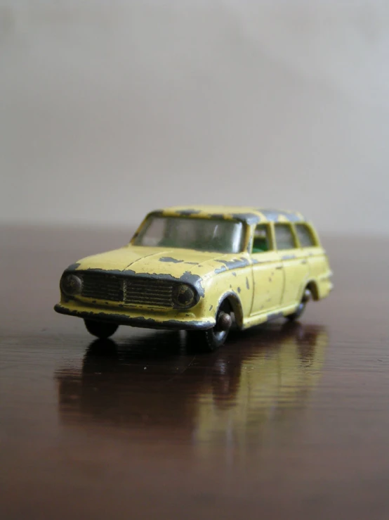an old toy yellow car sitting on top of a table