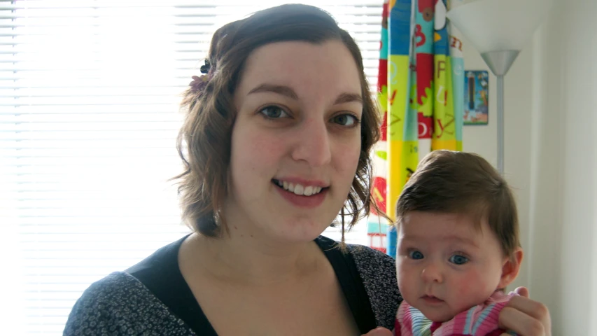 a woman standing next to her child in front of a window