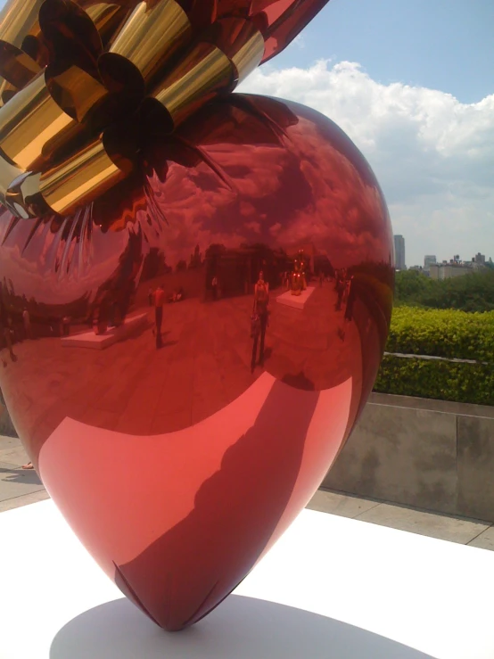 a shiny red vase is on display outside