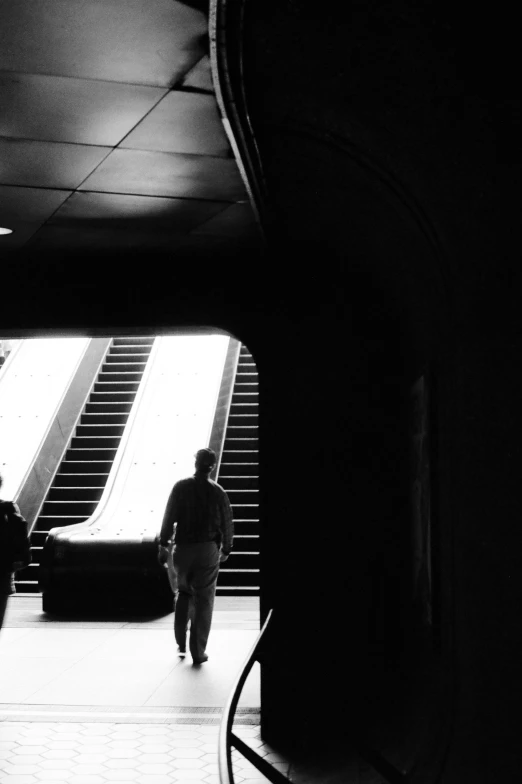 the person is walking down the walkway in the dark