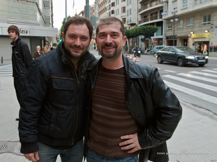 two men stand next to each other on the street