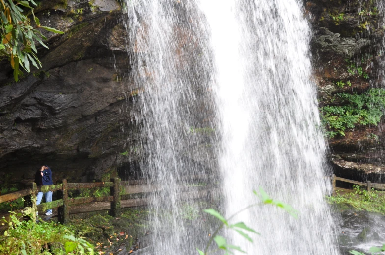 two people near a waterfall with a fence on the side