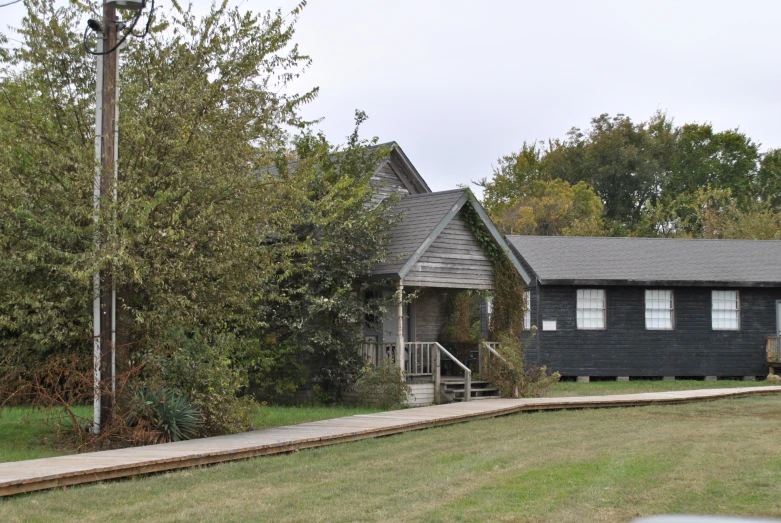 there is a black house near a tree and grass