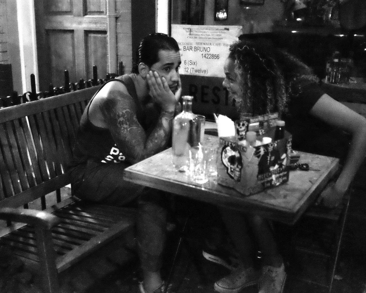 a black and white image of two people sitting at a table