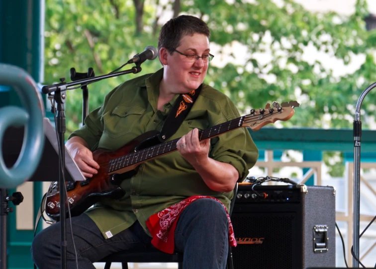 a man playing guitar on stage in front of microphones