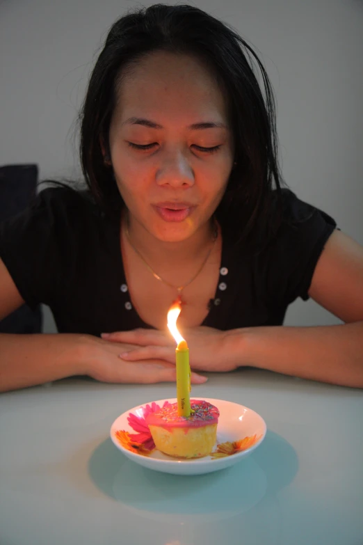 a woman blowing out a candle on a cupcake