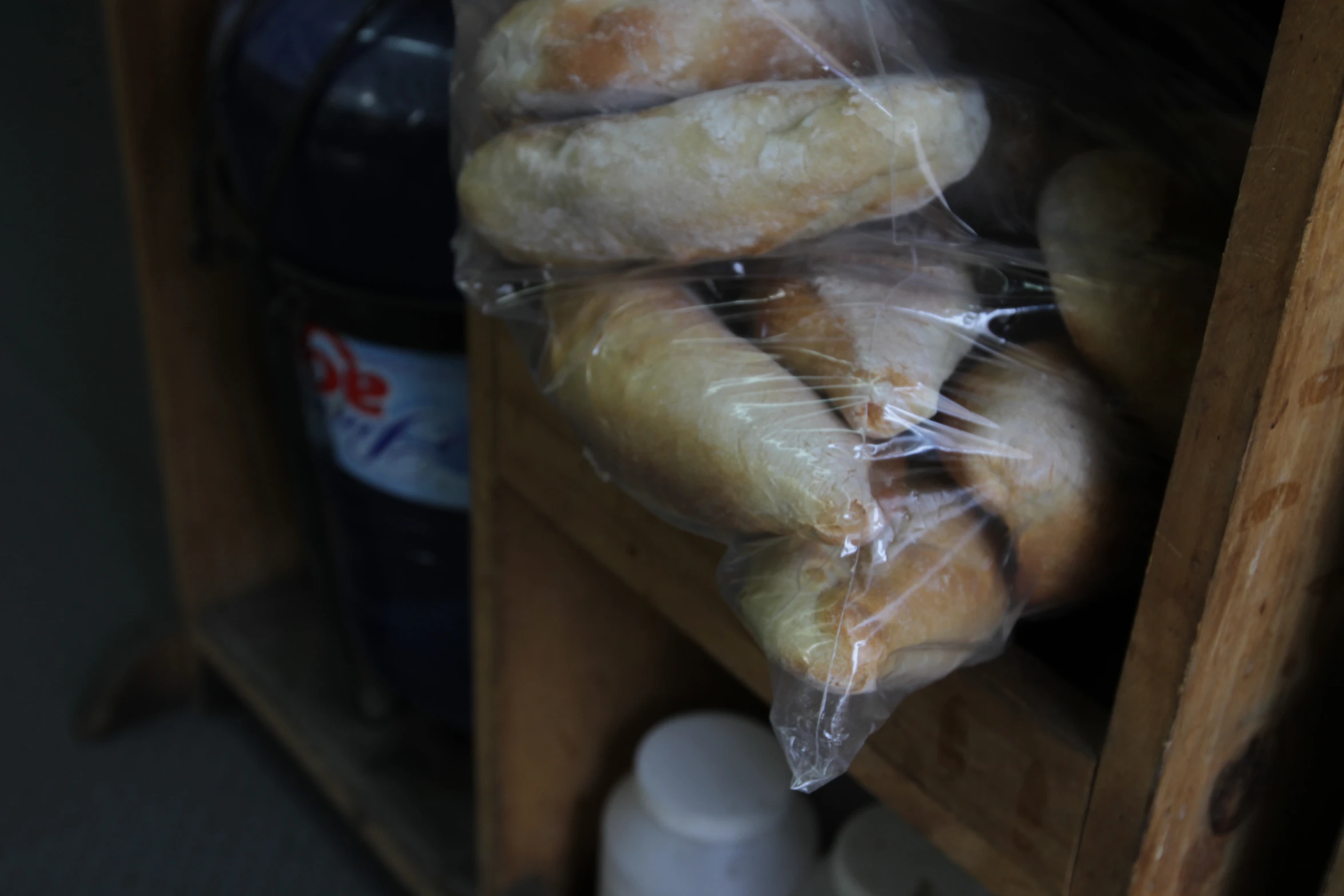 bagels wrapped in plastic on wooden shelves with blue bottles