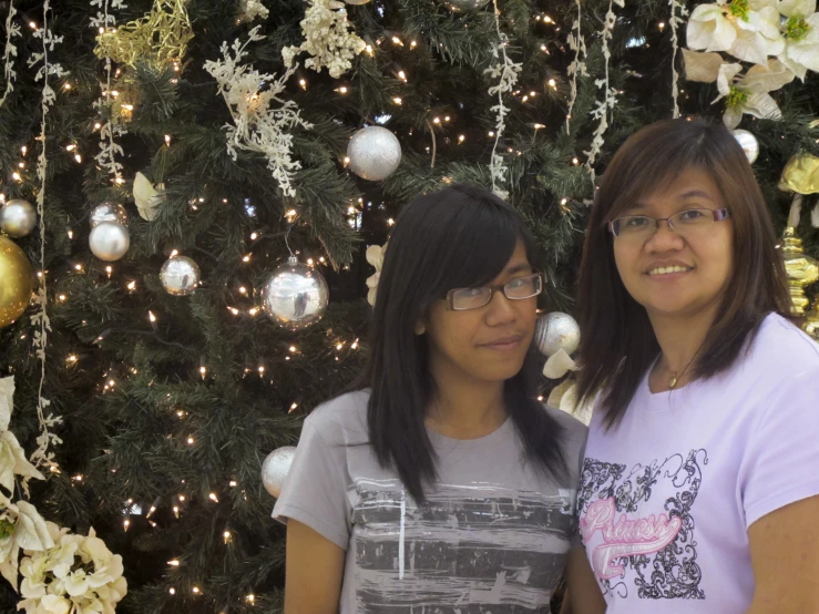 two women standing in front of christmas trees