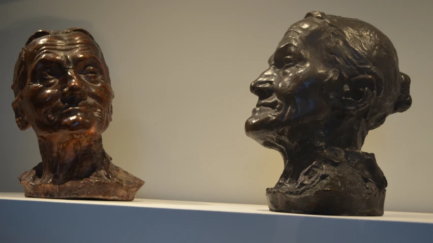 a pair of bronze heads sit on a shelf