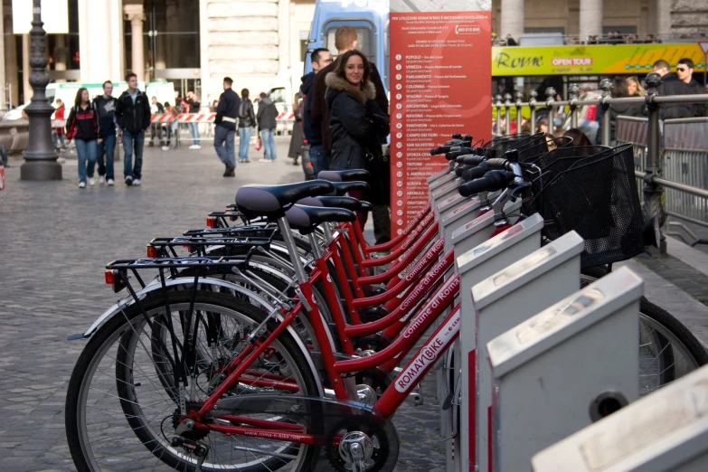 a row of bikes sit along a curb side on a city street