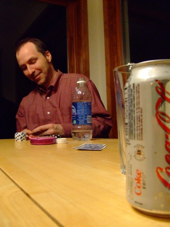 a man sitting at a table with an empty can of soda
