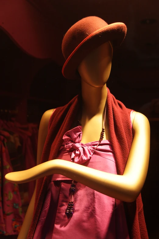 a mannequin dressed in a pink blouse and a brown hat
