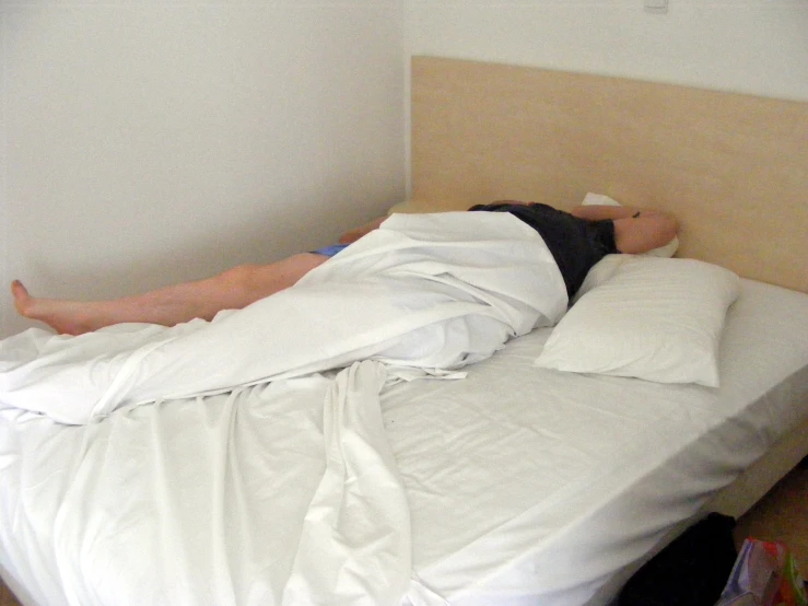 man lying in the middle of bed with no headboard