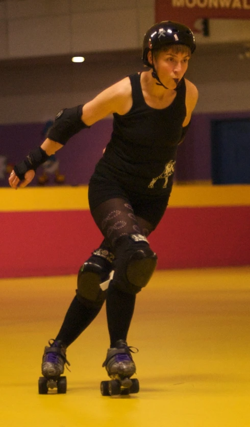 a female roller skater in a black shirt is riding a skateboard