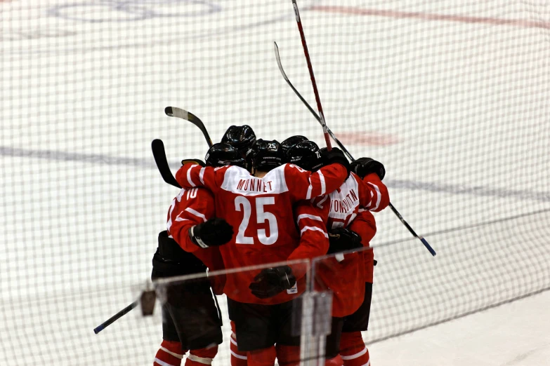 three red ice hockey players huddle together