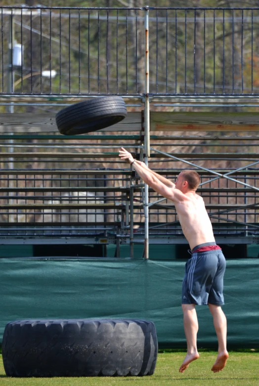 a boy catches a large tire on a grass area