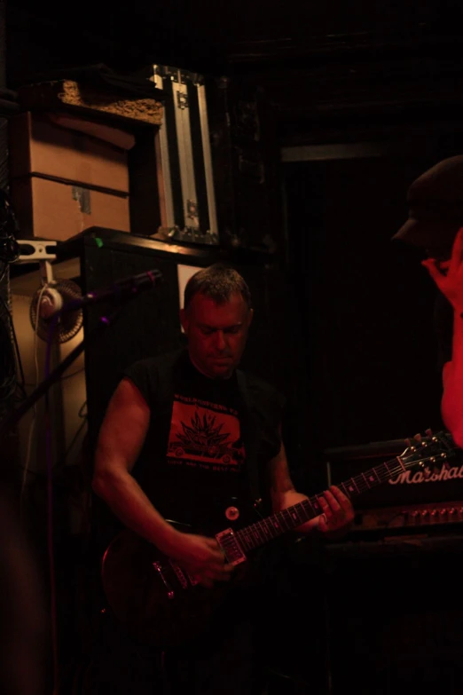 a man playing a guitar in front of some recording equipment