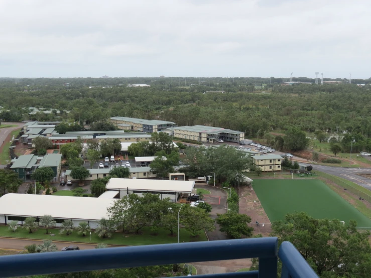 a town surrounded by green trees, and lots of parked cars