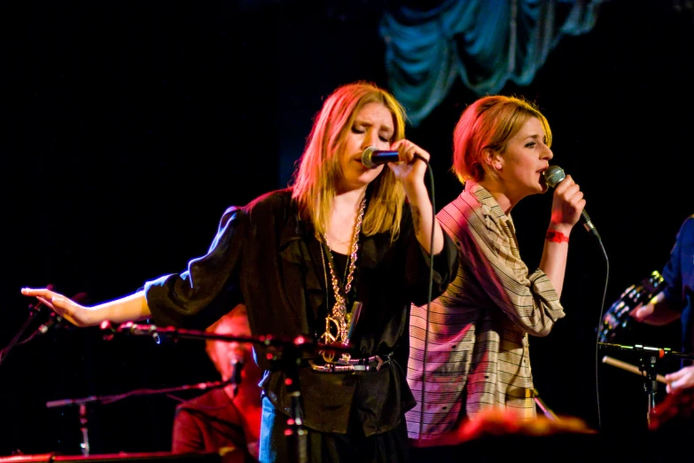 two woman singing into microphones at a party