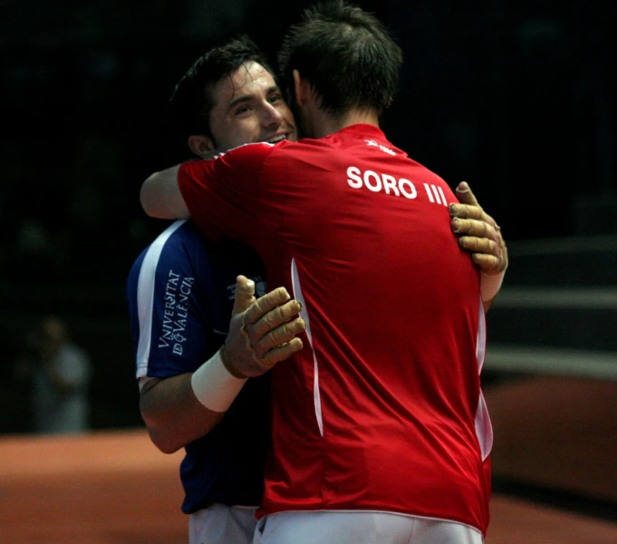 two men hugging on the tennis court together