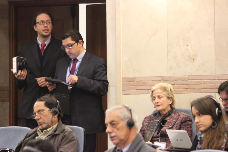 a person wearing a suit with headphones in front of some people