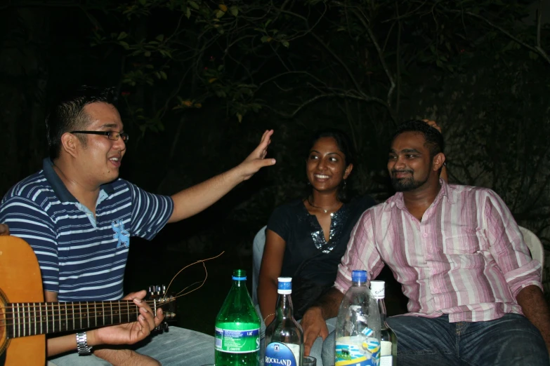 two people on a cell phone and one man holding a guitar