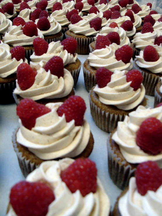 some type of cupcake on a silver tray with whipped cream and raspberries