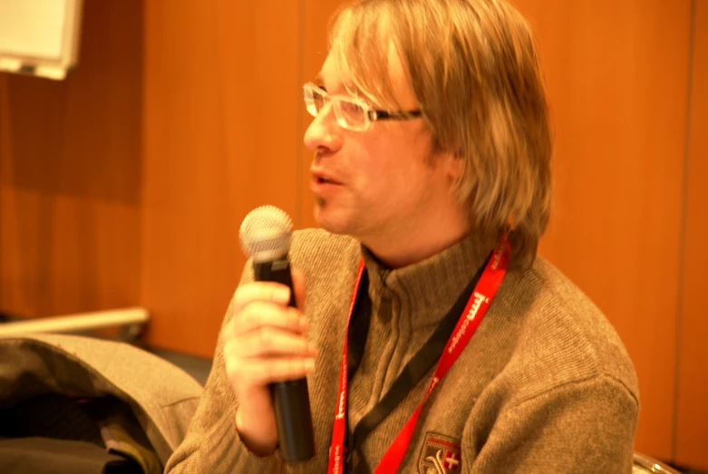 a man with a microphone standing next to a wall