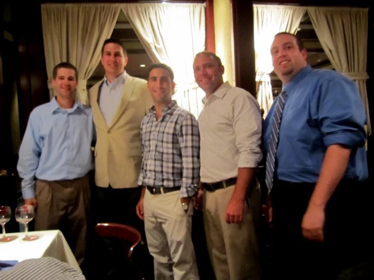 four men standing next to each other in front of a window