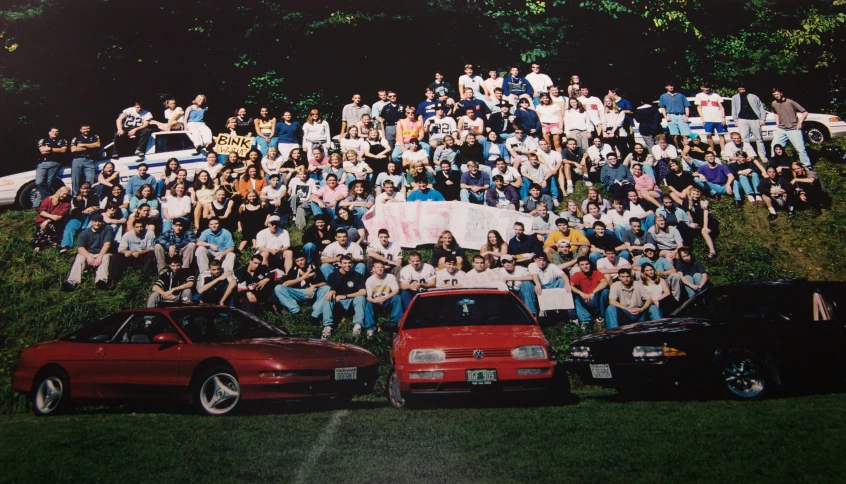 a group of people gathered in front of a parked car