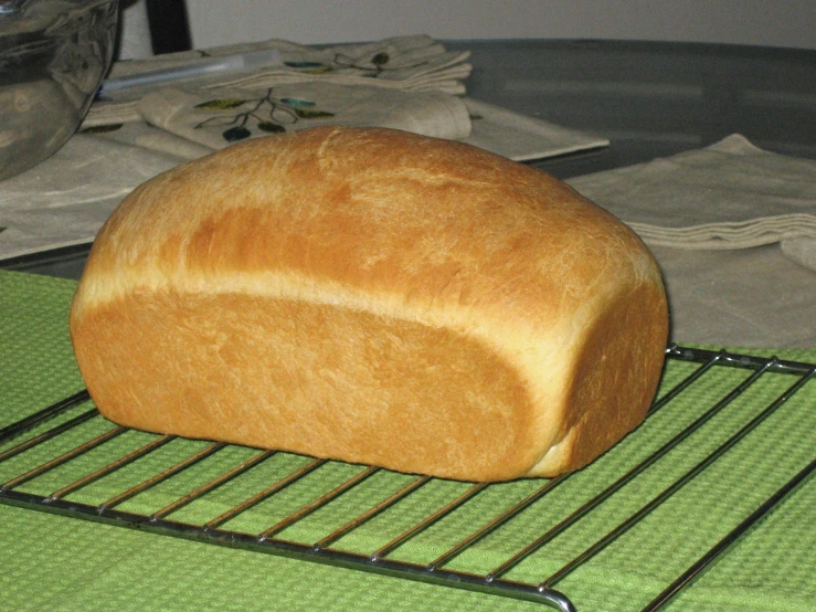 a loaf of bread cooling on top of a rack