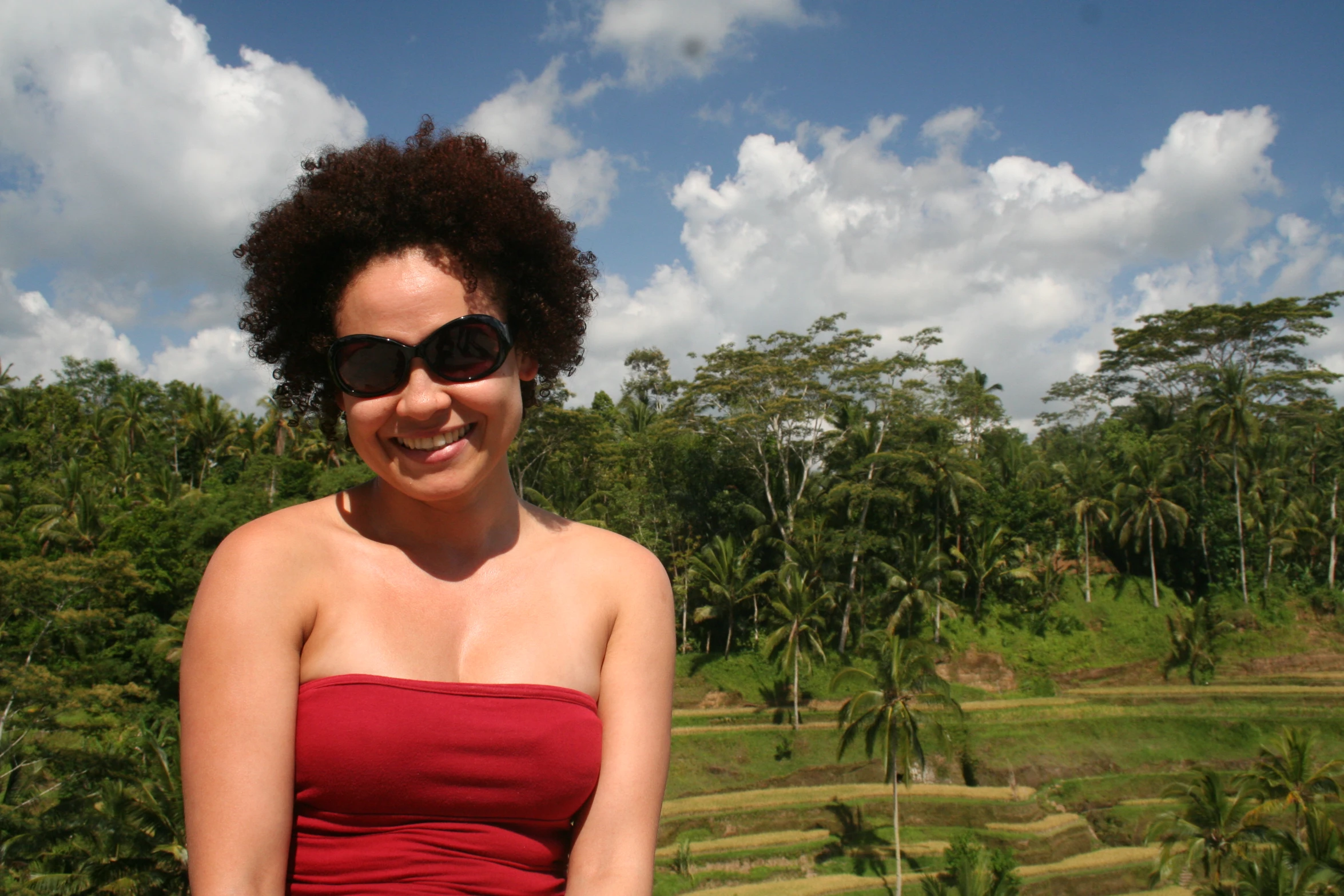 the woman is wearing a red strapless top and smiling